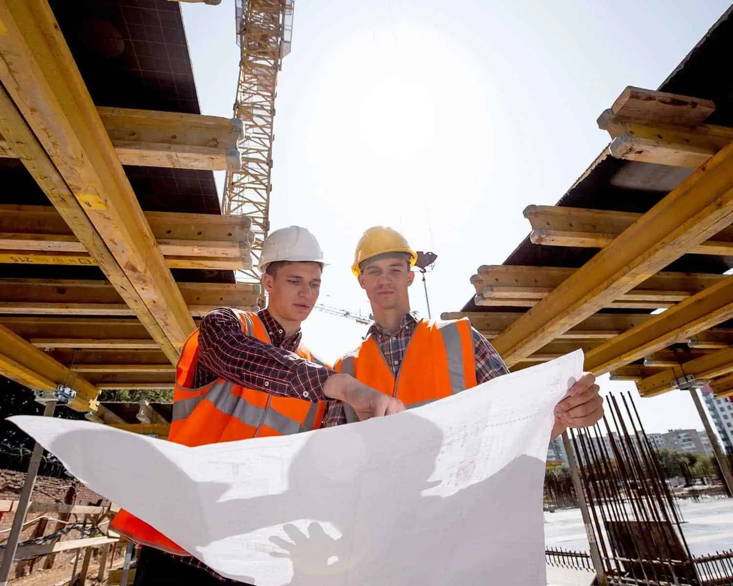 Two engineers reviewing blueprints at a construction site under development.