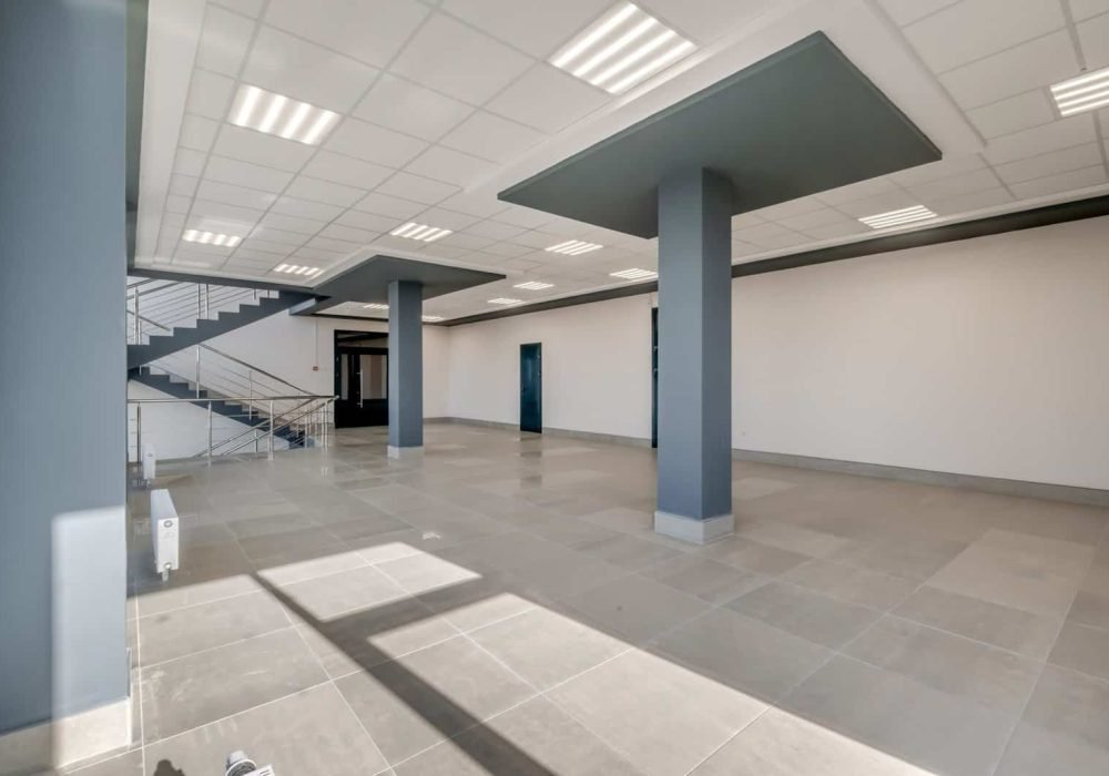 Interior of a commercial building with open layout, columns, and modern ceiling lighting.
