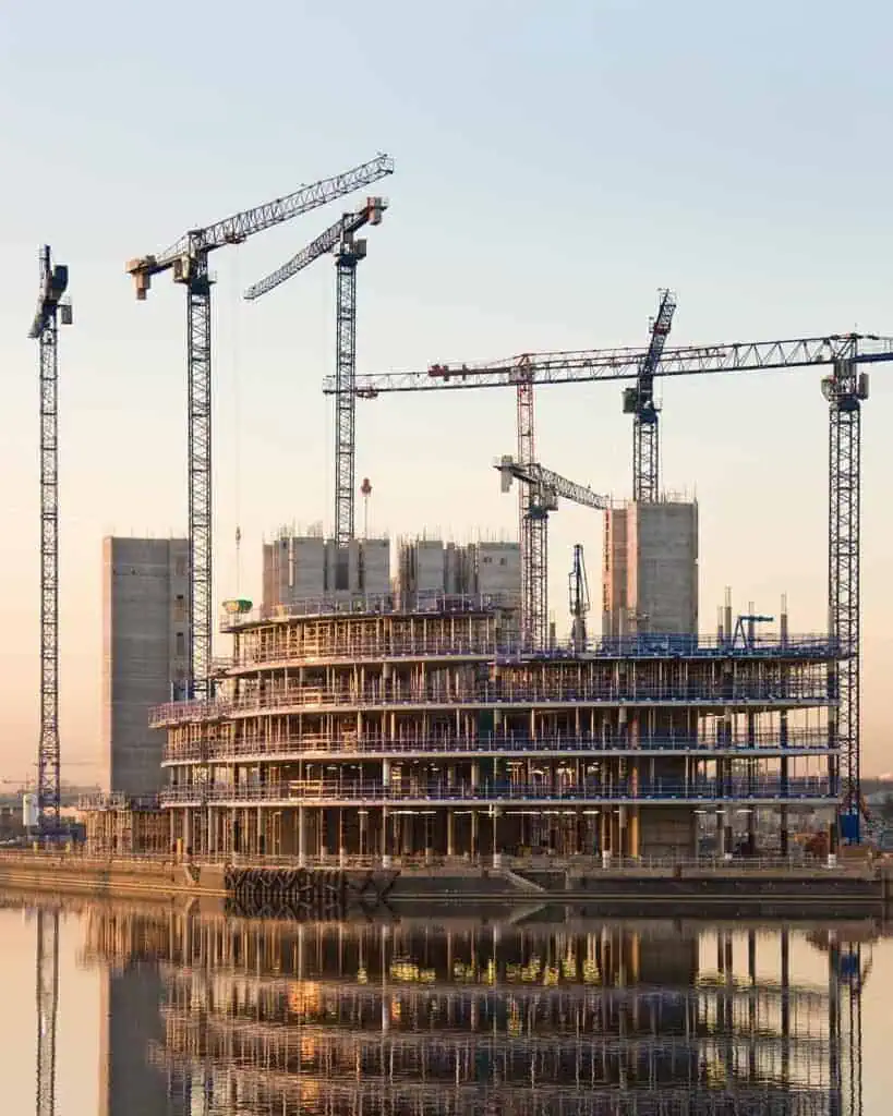 Construction site with multiple cranes and building framework.