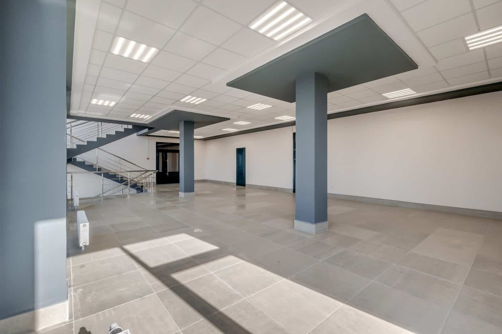 Interior of a commercial building with open layout, columns, and modern ceiling lighting.